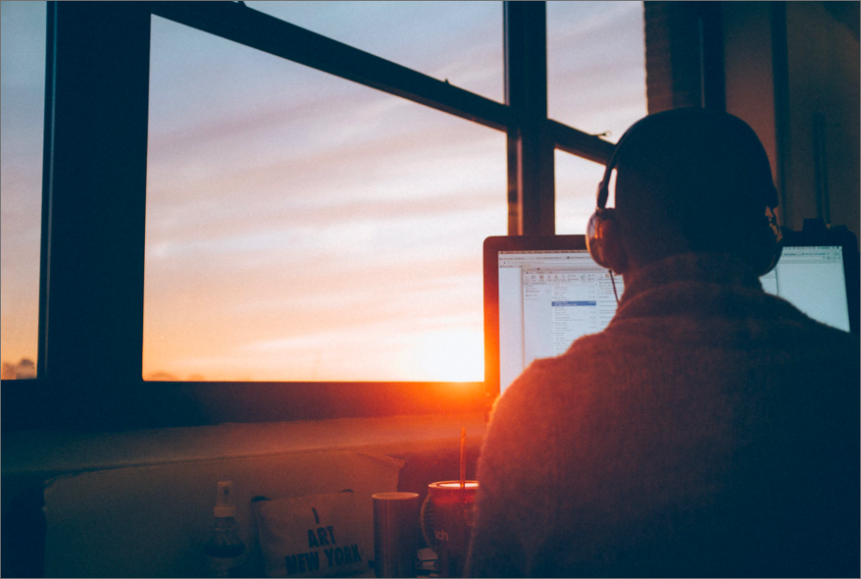 man working at computer with sunrise